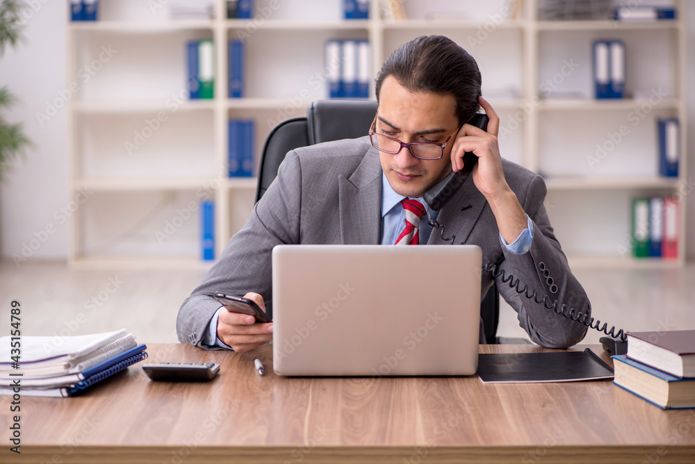 Wall mural young male employee sitting at workplace