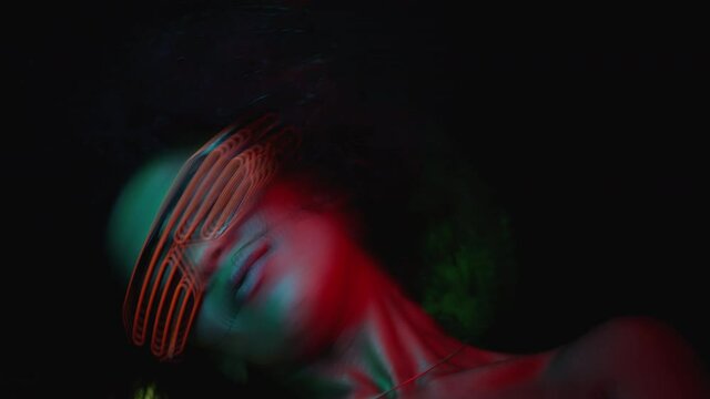 Amazing african woman dancing in nightclub under UV neon glowing lamps. Charming lady, night life concept. Modern pop outfit - fluorescent glasses. Visual echo effect.