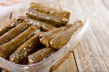 A closeup view of a container filled with stuffed grape leaves.