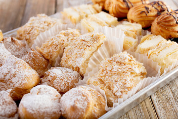 A view of a sampler of French pastries, featuring cream puffs, Napoleons, and eclairs.
