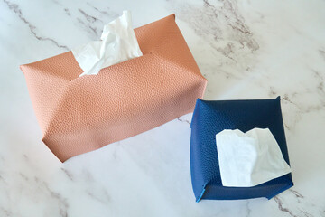 Tissue cases with different sizes and colors placed on a marble table.