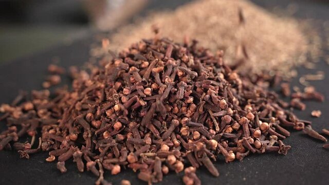 Close-up of cloves and spices with black background, industrial concept.