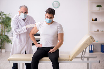 Fototapeta premium Young male patient visiting old male doctor in vaccination conce