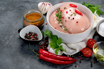 Raw chicken fillet prepared for cooking on gray background.