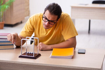 Young male student physics preparing for exams in the classroom