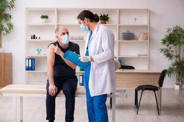 Fototapeta premium Old man visiting young doctor in covid-19 vaccination concept