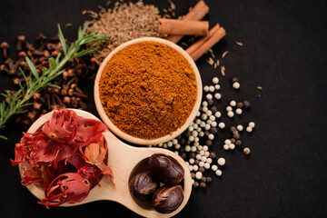 Close up of Curry powder and spices in a wooden cup with black background, industry concept