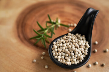 White pepper in spoon and with black background, industrial concept