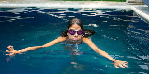 Girl swimming in pool on sunny day