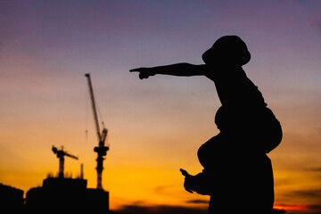 The silhouette of the happy father and son wearing a construction helmet holding hands expressing...