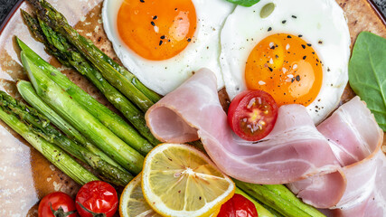 Ketogenic, keto diet. brunch breakfast. fried eggs, green asparagus, bacon, ham and and cherry tomatoes. Healthy food