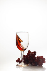 Red wine in glass with red grape.