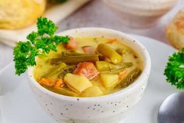 Vegetable soup made from cut green beans, carrot, potato and ham.