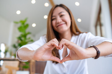 A beautiful asian woman making heart hand sign with feeling happy