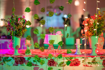 Birthday cake on the head table surrounded by colorful lighting and decorative arrangements. 50