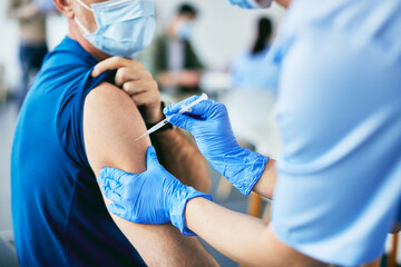 Close-up of man receiving coronavirus vaccine at vaccination center.