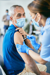 Mature man getting vaccinated against COVID-19 at vaccination center.