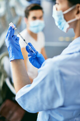 Close-up of nurse doing immunization of people against coronavirus at vaccination center.
