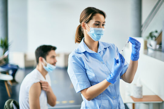 Ypung nurse preparing coronavirus vaccine during immunization at vaccination center.