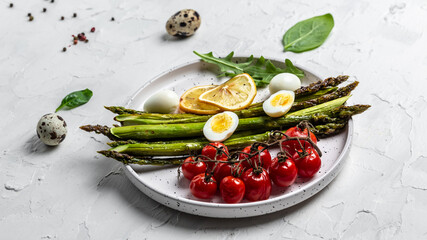 Salad baked asparagus with lemon, cherry tomatoes and boiled quail eggs. Healthy food, diet menu. Top view, overhead, banner