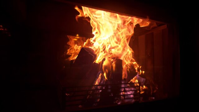 SLOW MOTION, CLOSE UP: Idyllic shot of logs burning inside a firepit in the living room on a cold night. Picturesque shot of a romantic fire burning inside a vintage fireplace in a dark luxury house.
