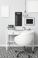 Modern workplace with laptop and organizer near light wall