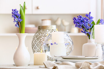 Beautiful composition with hyacinth flowers and burning candles on dining table