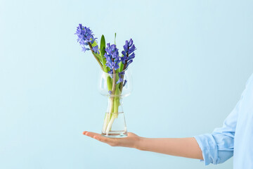 Woman holding vase with beautiful hyacinth flowers on color background