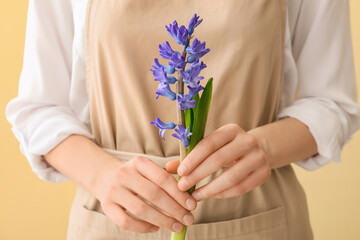 Woman holding beautiful hyacinth flower on color background, closeup