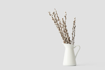 Jug with willow branches on white background