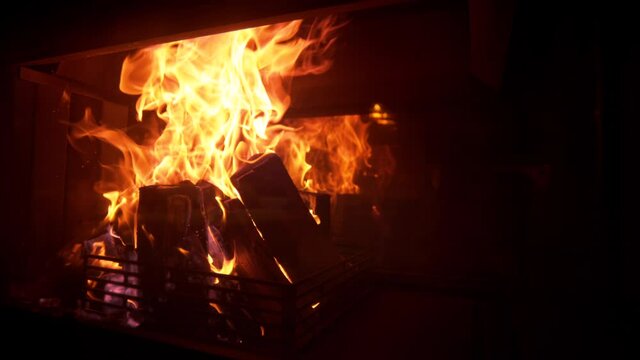 SLOW MOTION, CLOSE UP: Picturesque shot of a romantic fire burning inside a vintage fireplace in a dark luxury house. Idyllic shot of logs burning inside a firepit in the living room on a cold night.