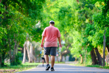 Fat man exercising By walking to burn fat And run slowly to exercise in the park