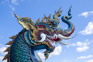 Fototapeta na wymiar Head of a blue dragon against the sky. Buddhist temple Wat Rong Seur Ten (Blue Temple). Chiang Rai, Thailand