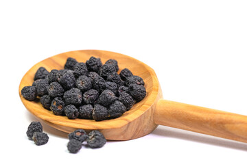 Getrocknete Aroniabeeren auf einem Holzlöffel vor weißem Hintergrund