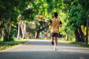 Back view of young man jogging or running exercising outdoors in park, Concept of healthy lifestyle.