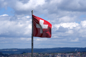 Swiss flag blowing in the wind with cityscape of Zurich in the background at springtime. Photo taken May 22nd, 2021, Zurich, Switzerland.
