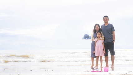 Smile family on the beach. Mother, daughter and father against sea and sky background. Happy holiday travel concept.