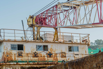 Fototapeta na wymiar Crane boom attached to upper deck of old rusty abandoned barge.