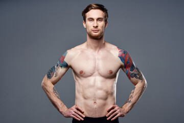 Fototapeta na wymiar sporty man tattoos on his arms naked torso bodybuilder gray background