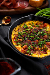 Egg omelet with sausage and seasonings in a cast iron pan close up, vertical photo with soft focus