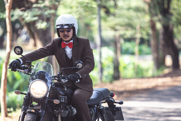 Fototapeta na wymiar Rider riding modern classic motorcycle with suit look like gentleman for men campaign. Rider happy in freedom lifestyle travel by motorbike.