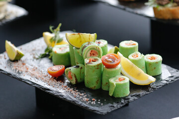 Set of rolls of avocado, cream cheese and red fish with a lemon and lime wedges