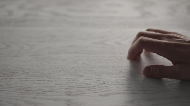 Closeup man hand finger tapping oak wood surface