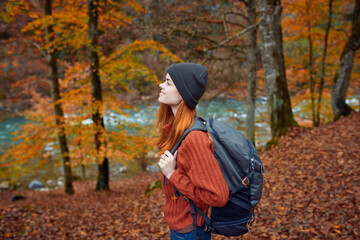 woman hiker walks in the forest in autumn in nature near the river and leaves landscape