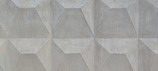 Part of a concrete fence with a geometric pattern. A light gray concrete fence panel on which a...