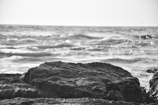 waves and rocks standing against each other black and white photo