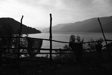 Black and white image with fencing, lake and mountains during monsoon season