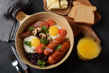 Traditional full English breakfast with bacon, fried eggs, sausages, baked beans, mushrooms.