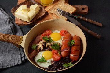 Traditional full English breakfast with bacon, fried eggs, sausages, baked beans, mushrooms.