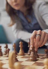 Woman playing chess and moving a piece